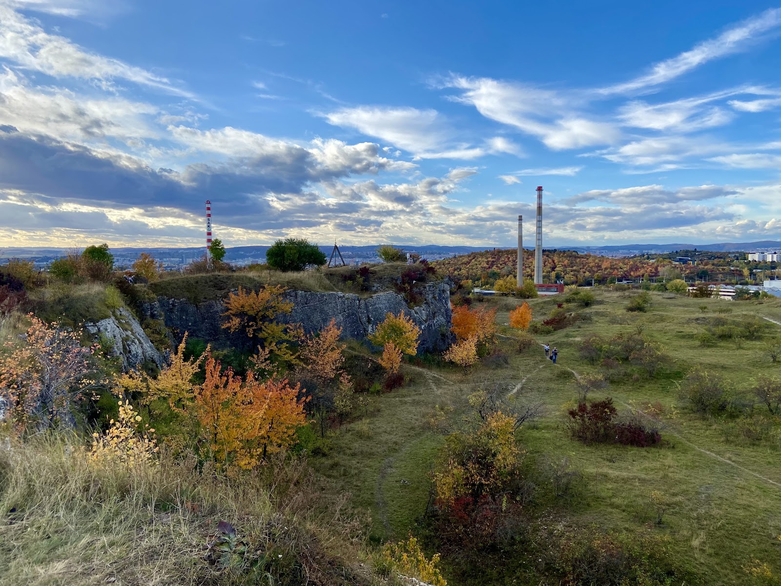 Podzimní panorama Stránské skály s barevnými stromy a komíny.